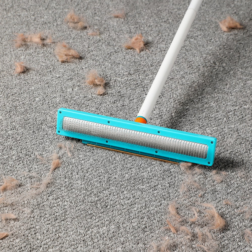 Brass scraper side of the Jolllax Carpet Rake removing surface hair and lint from low-pile carpet.